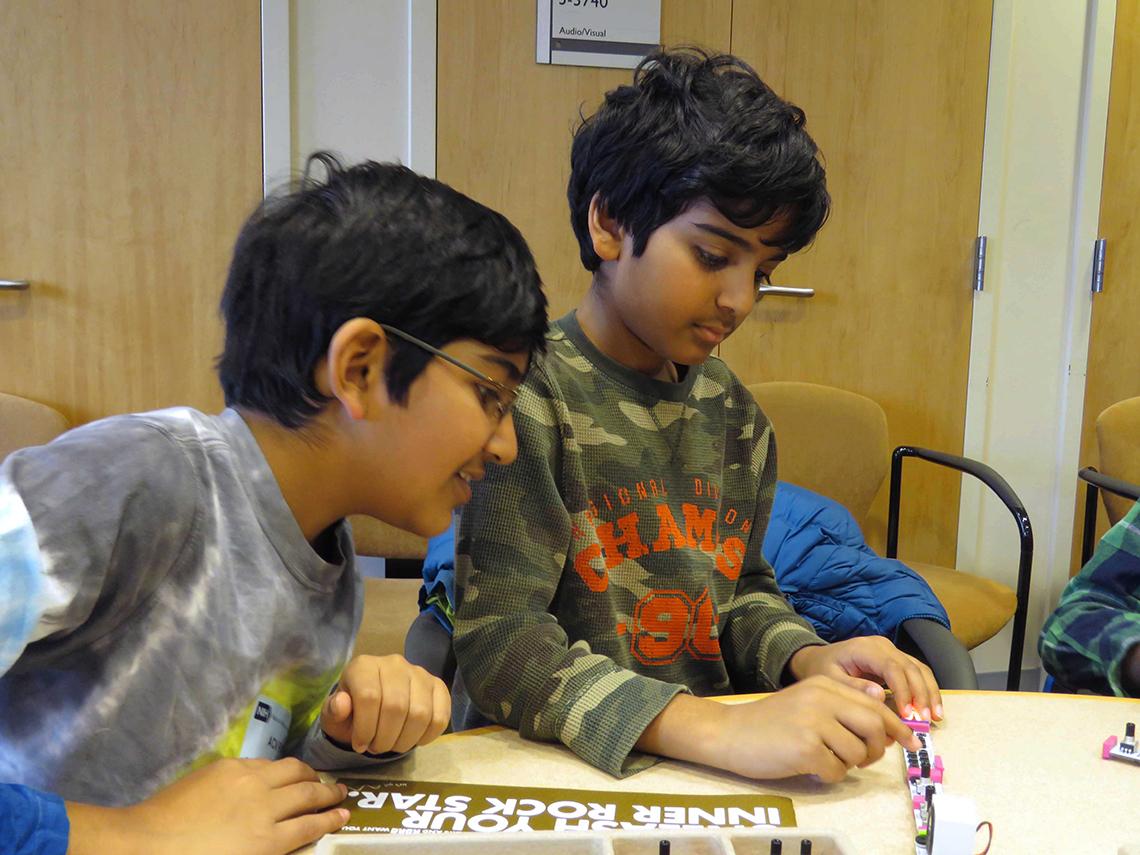 Two kids listen to a sound generator