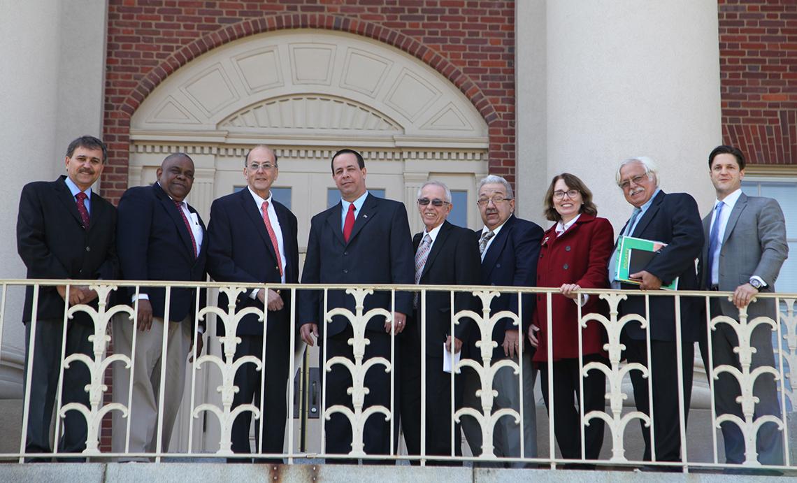 Several people stand in front of a railing