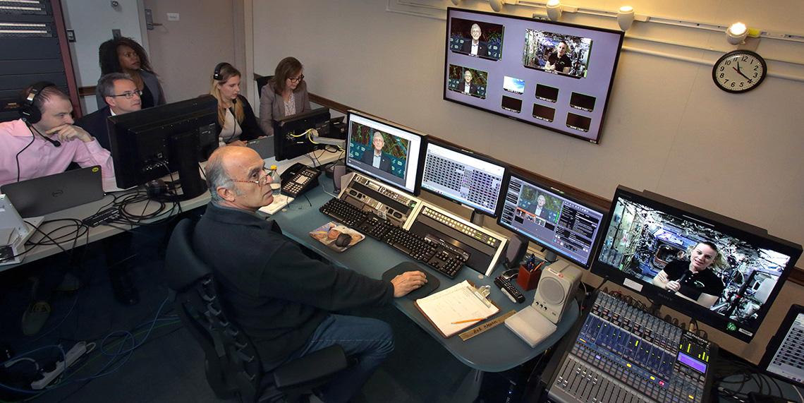 Staff utilize sound board, several computers and monitors and other equipment.