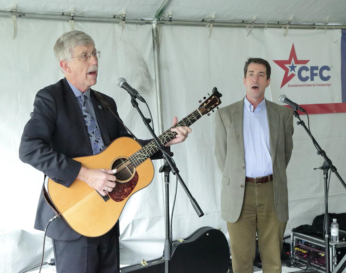 Collins sings and plays guitar with Austin under a large tent.