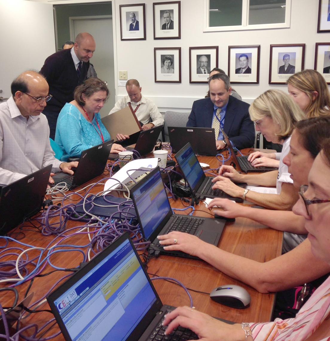 Lorsch and staff members seated around table with laptops.