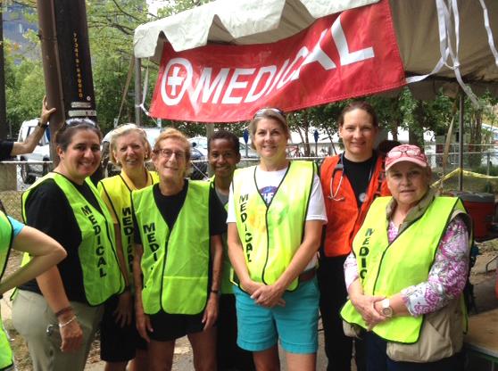 Small group of people wearing safety vests smiles into camera.