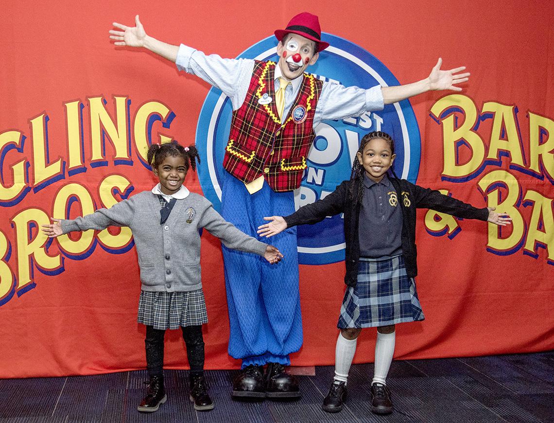 Kids and clown stretch out their arms for photo at Verizon Center before show. 