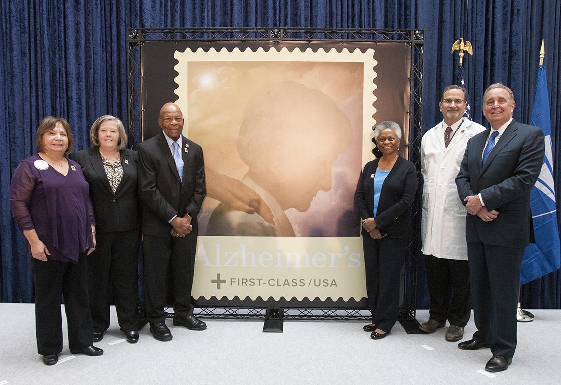 Group stands next to stamp image.