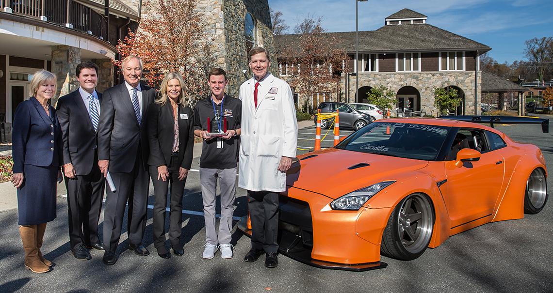 Andrew Lee and family greet Dr. Linehan in front of sports car.