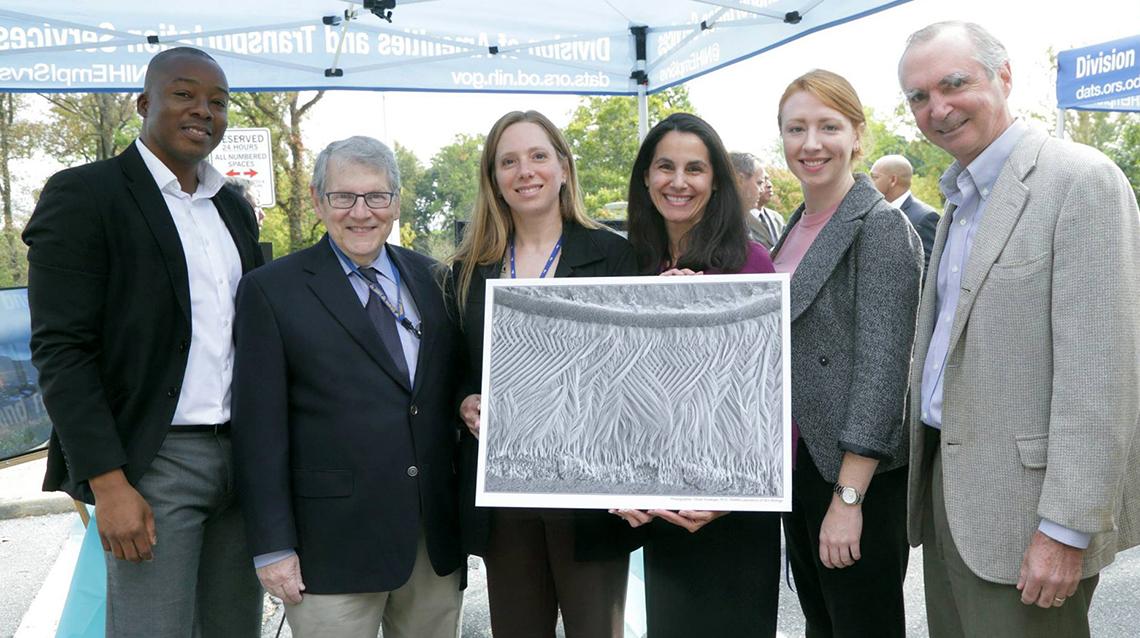 NIAMS colleagues hold art submitted in the IC directors art challenge.