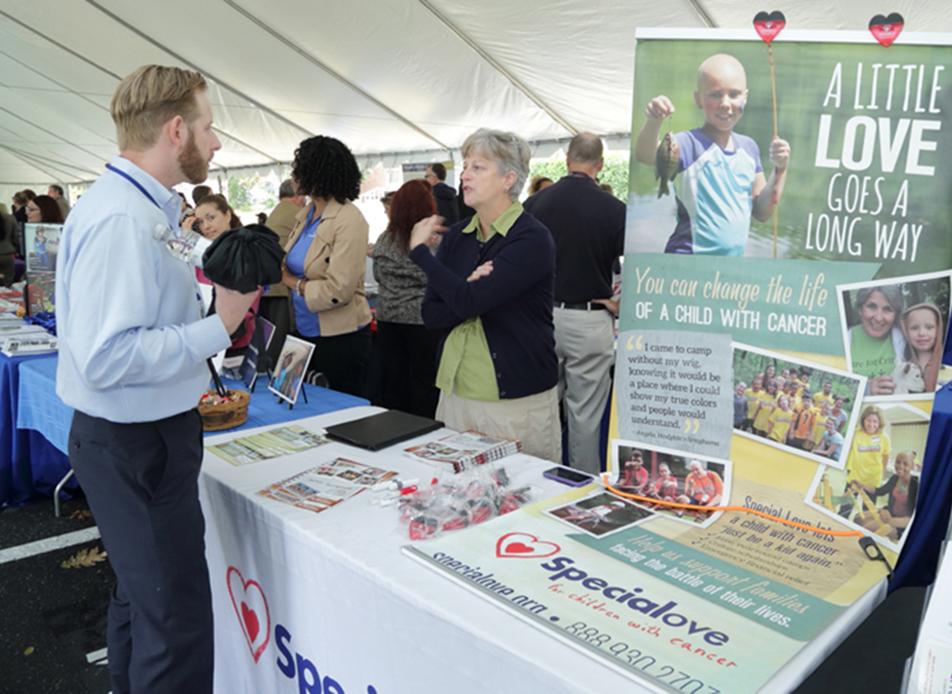NIH'er talks with Special Love rep at information table.