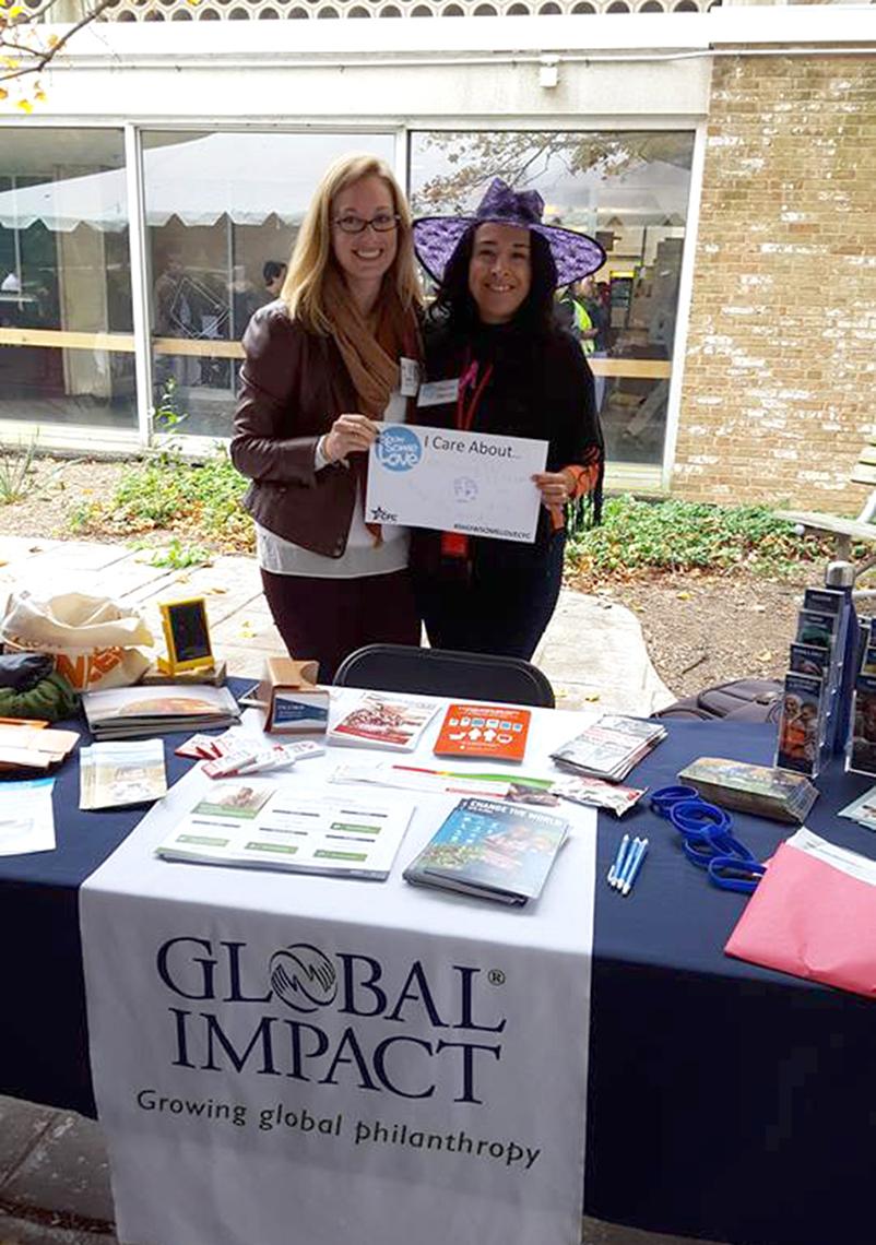 Two employees from Global Impact staff an information table.