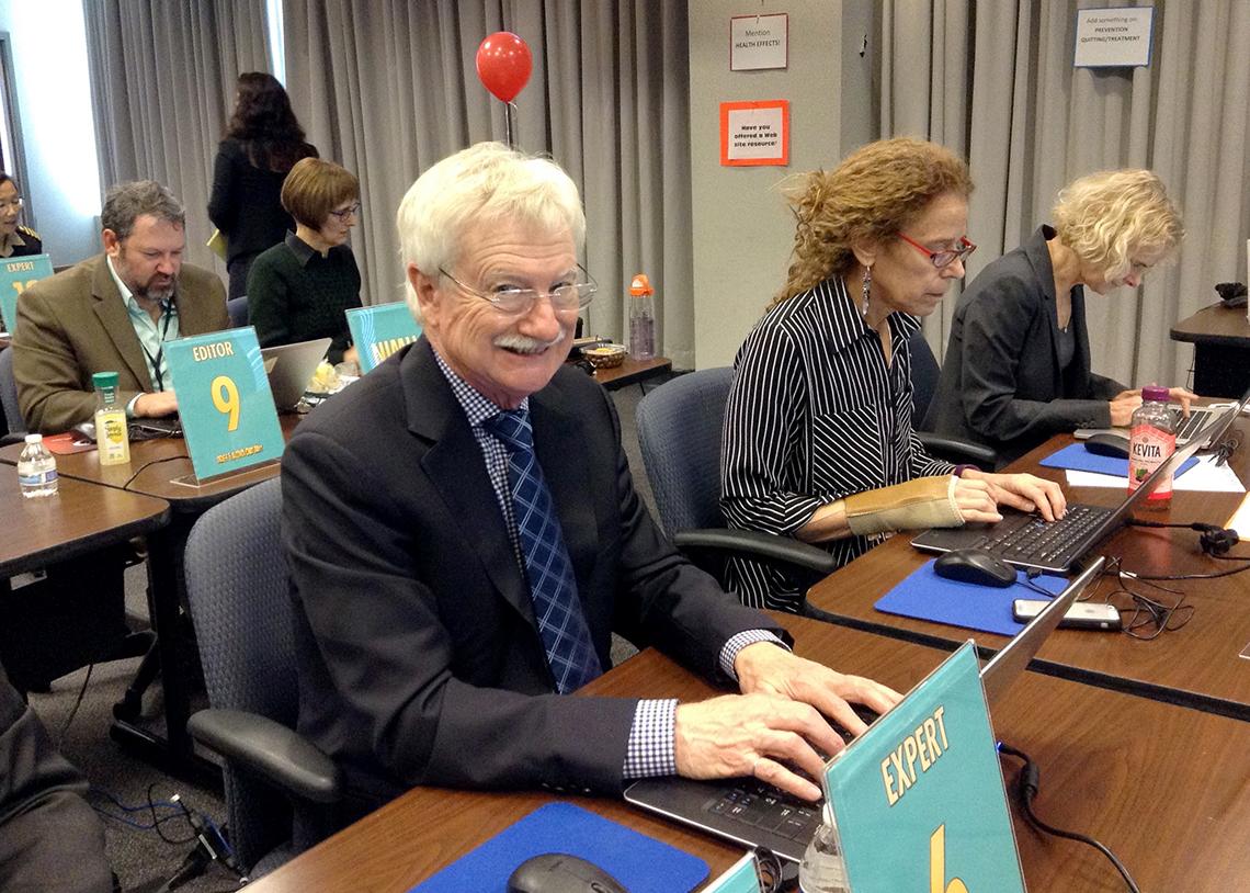 In a conference room, laptop stations are staffed by several individuals.