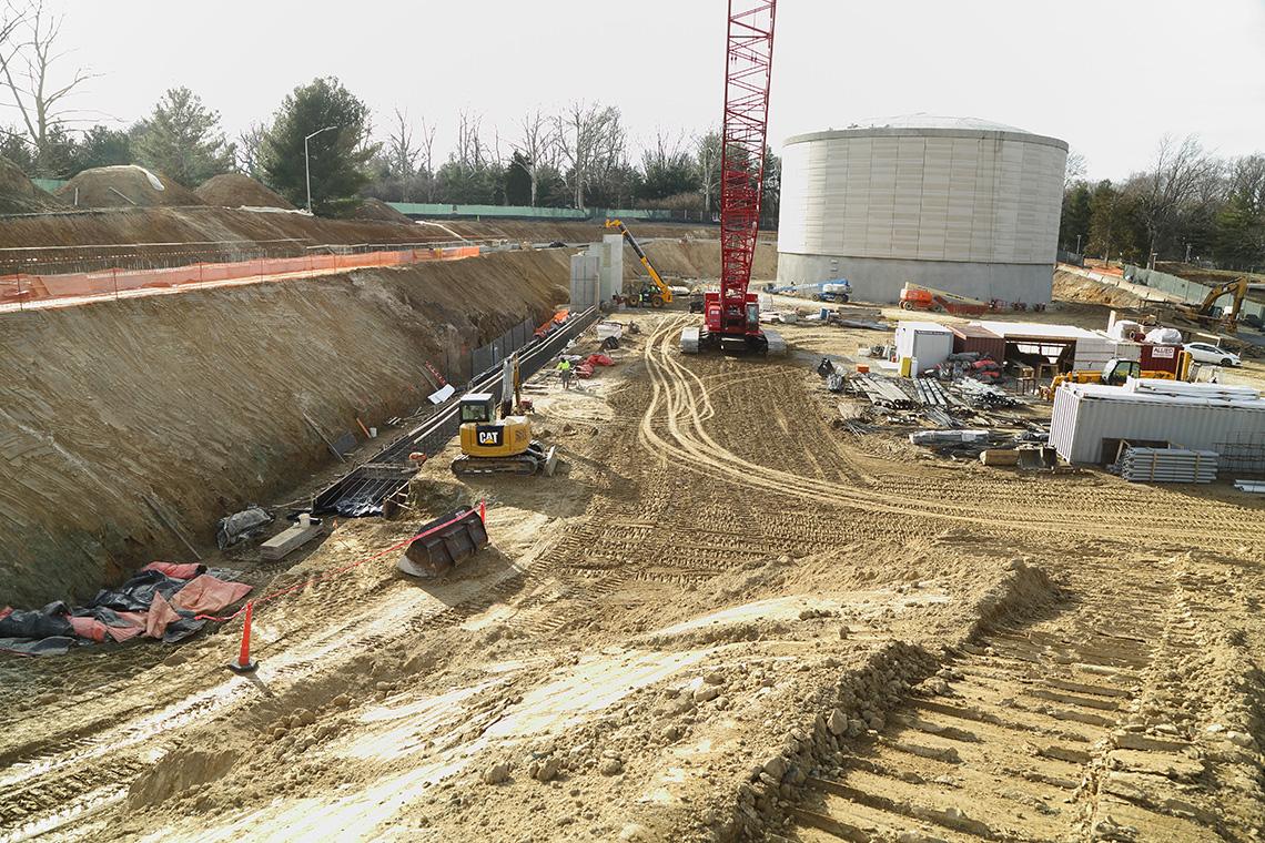 Excavated hole with various construction vehicles and materials scattered around it