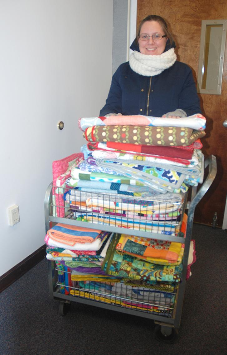 Employee delivers cart full of quilts.