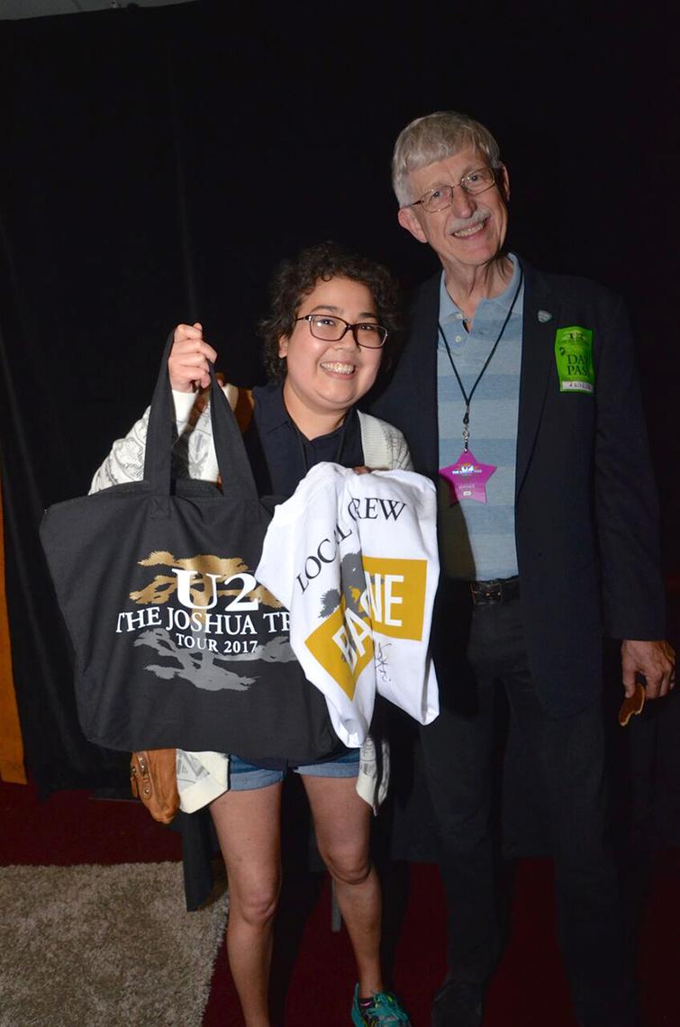Ness  holds up a tote bag and a t-shirt with Collins