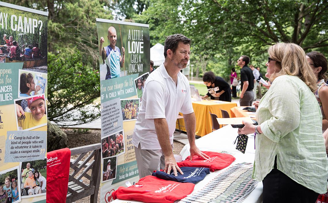 A woman chats with Smith at information table for Camp Fantastic