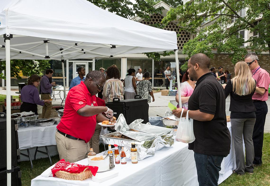 A volunteer loads up a plate of barbecue under the tent outside Bldg. 10.
