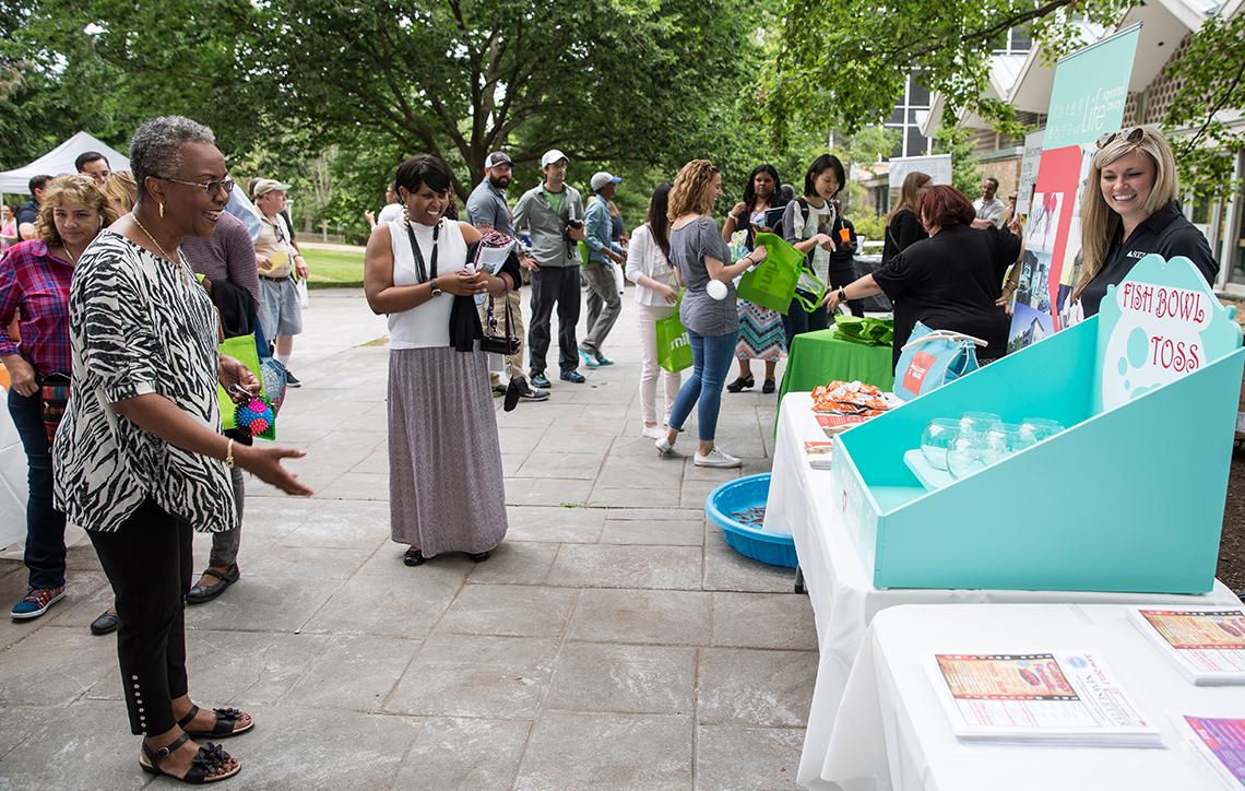 A woman tosses a plastic fish into a bowl at Camp Fantastic fundraiser.