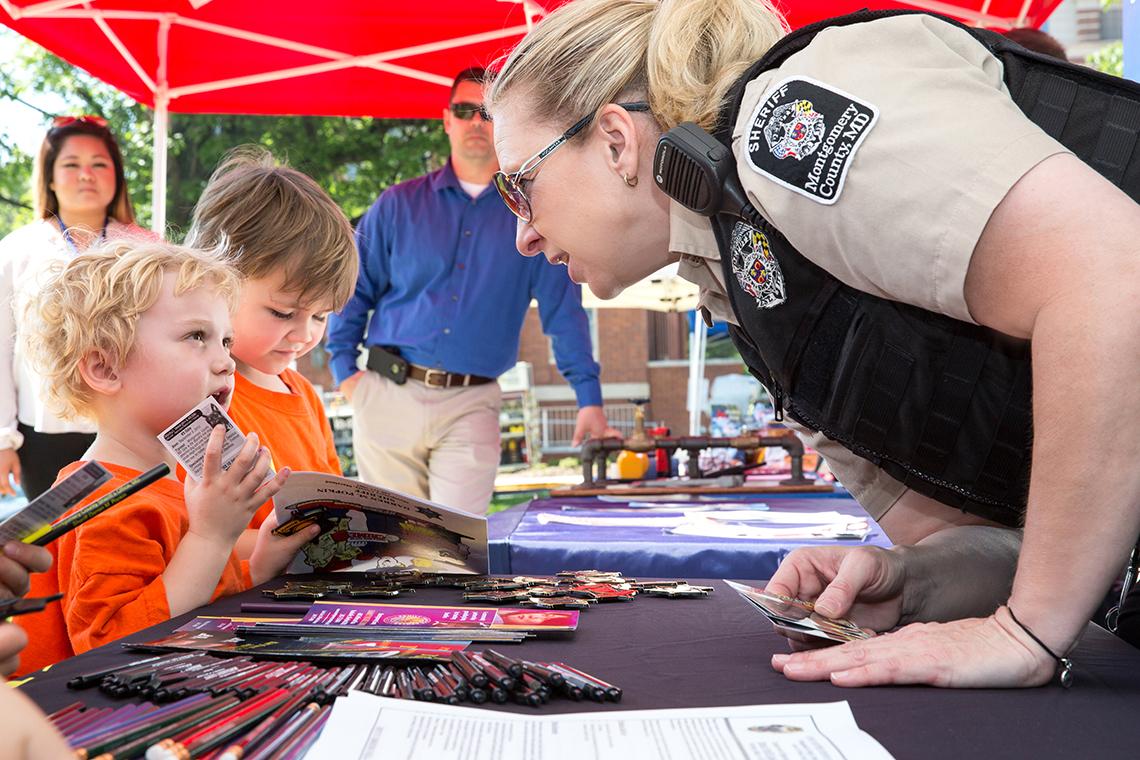Meiklejohn leans across a table to chat with a young child.