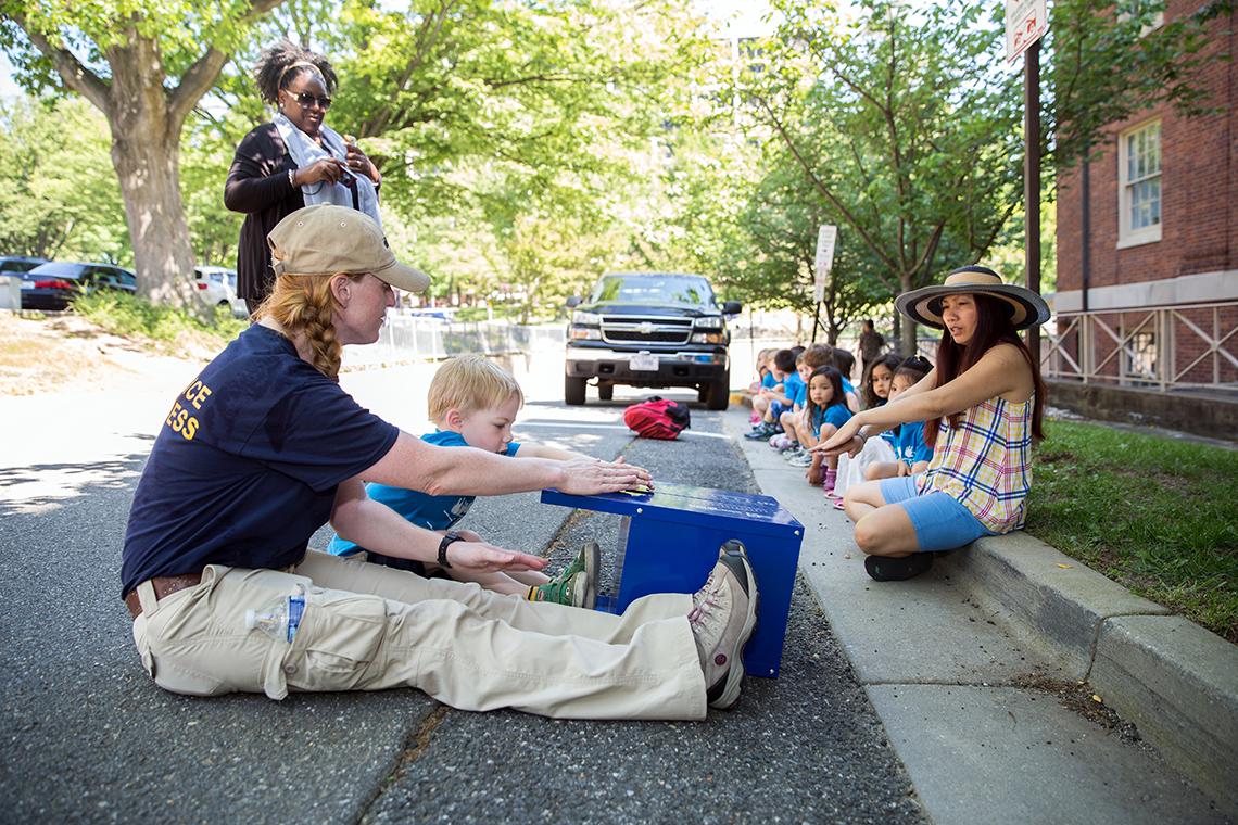 Fedorisko and youngster seated side by side on the sidewalk, performing exercises.