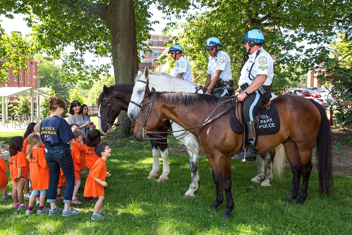 Young children approach officers on horseback. 