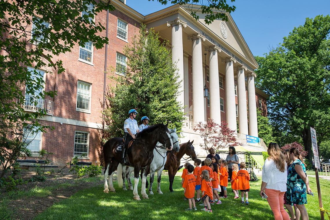 Young children approach officers on horseback. 