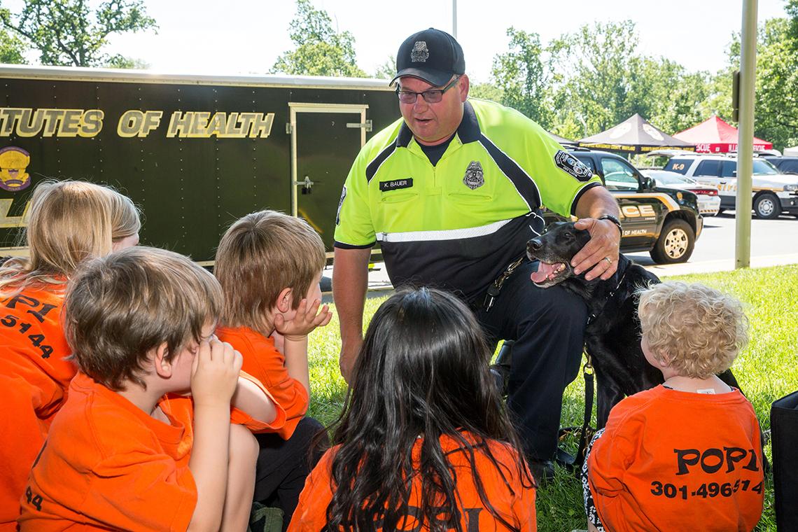 With his hand around a police dog, Bauer talks to several youngsters.