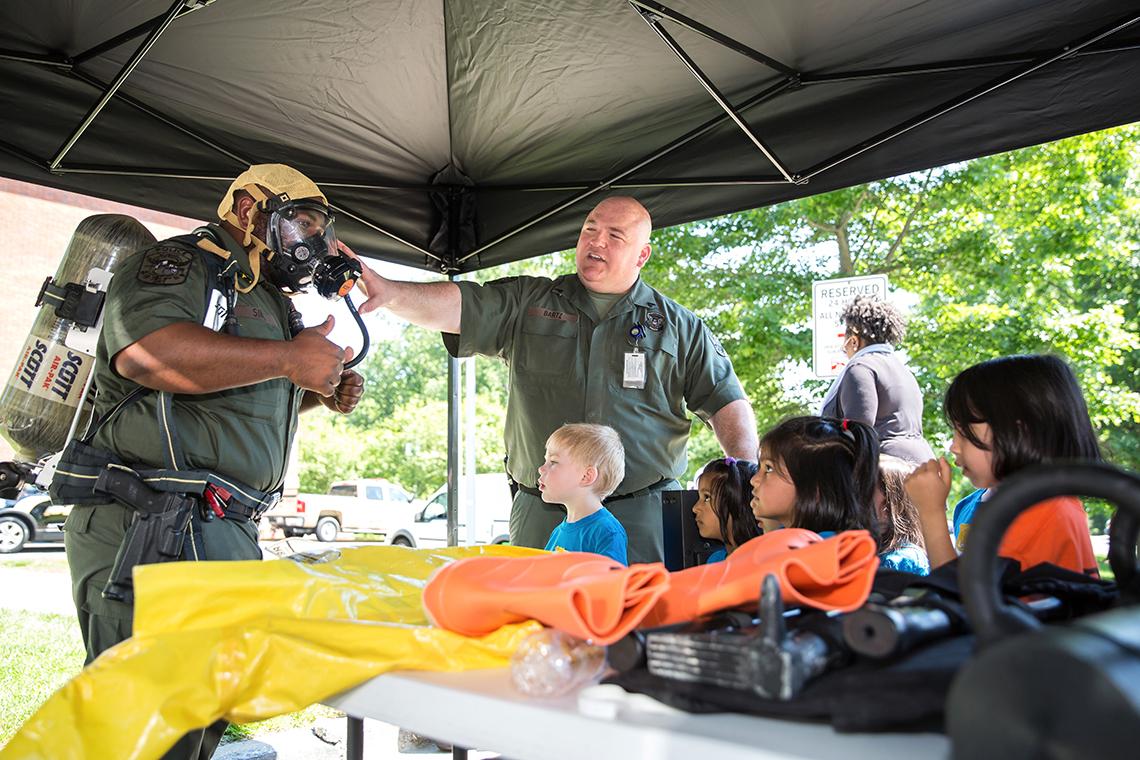 Sims wears gas mask as Bartz adjusts it, with several kids looking on.
