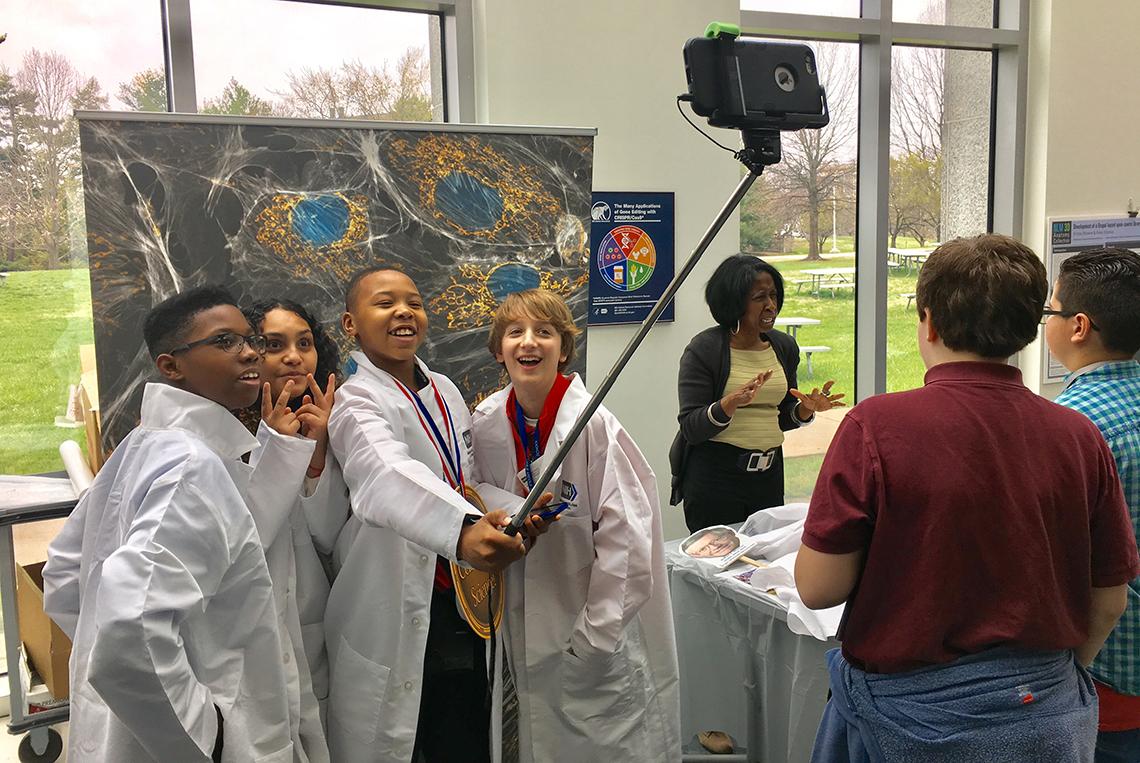 Students wearing lab coats take a selfie