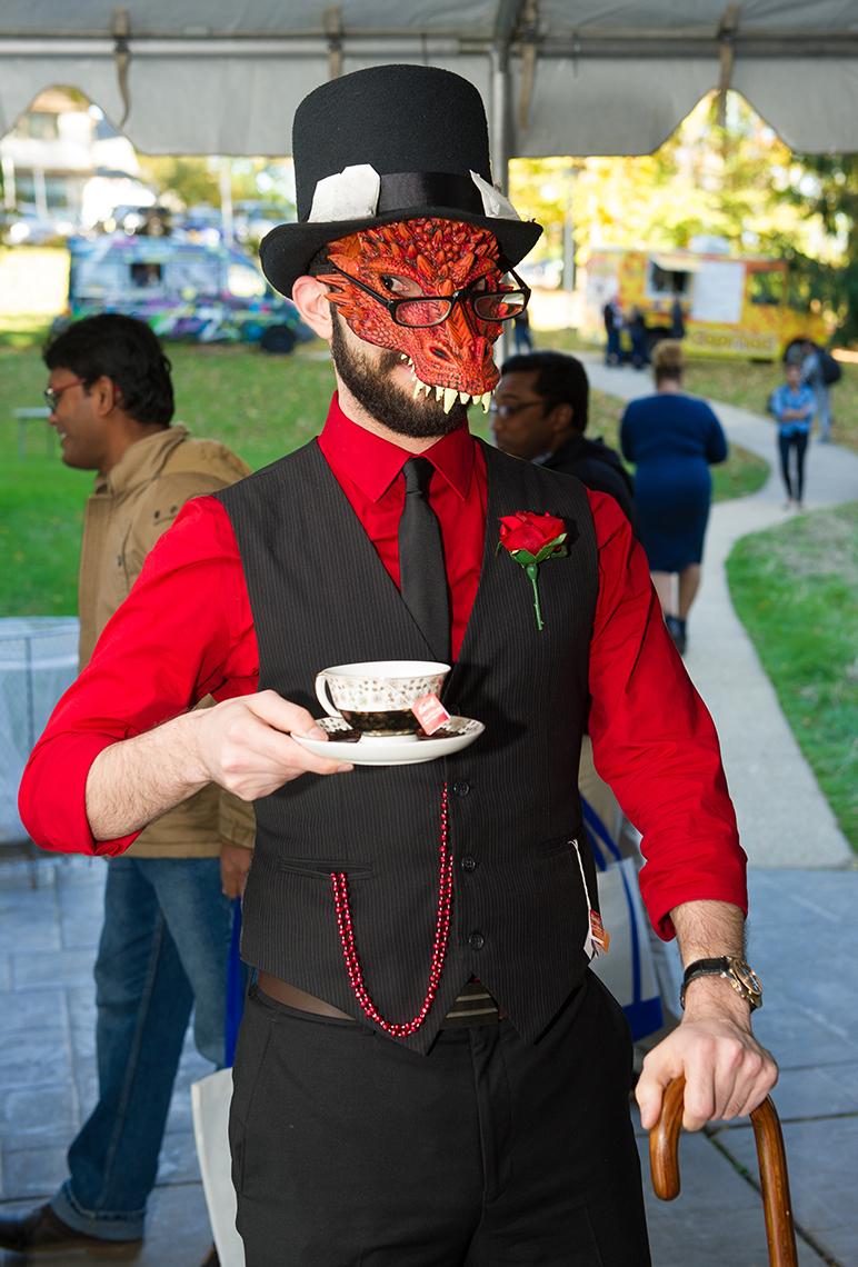 An NIH'er dressed in red and black and monster mask leans on a cane, holds a cup of tea