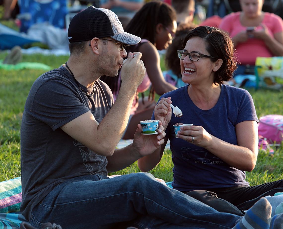 A smiling couple enjoys ice cream on the lawn.