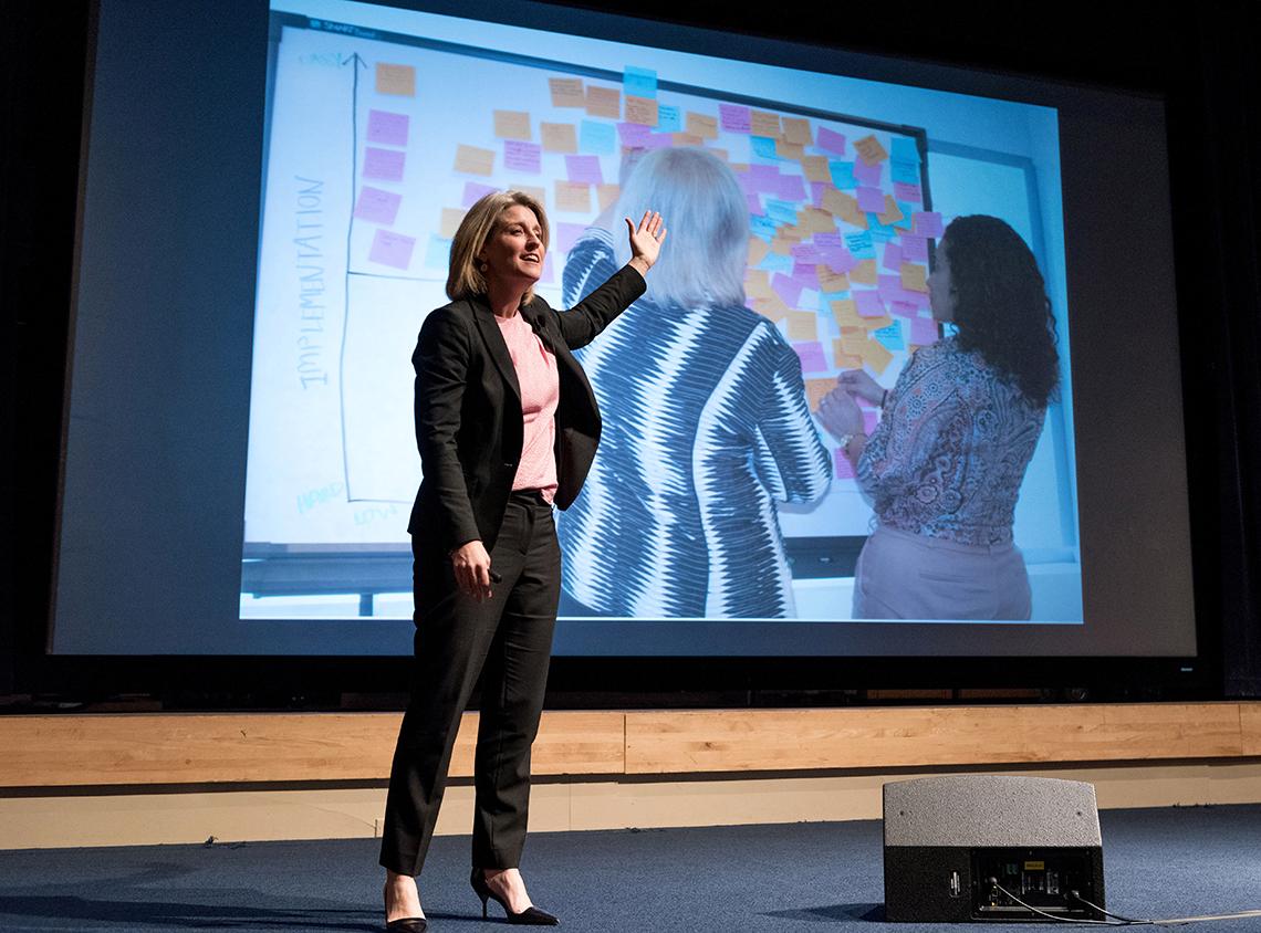 Bodell onstage gesturing to a slide