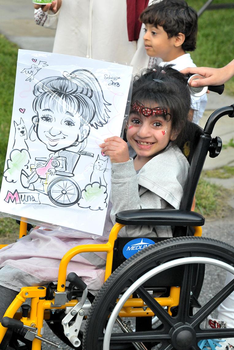 Muna Albusaidi, 8, beams as she shows off the caricature of her made at the inn's summer carnival.
