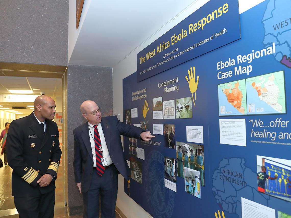 Adams and Gilman look at Clinical Center exhibit on Ebola
