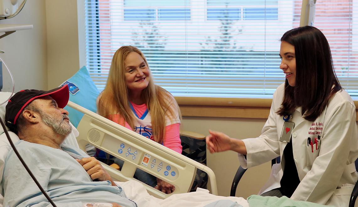 Lying in a hospital bed, Garces-Soto, with his wife Lyssette seated beside him, chats with Dr. Apolo.