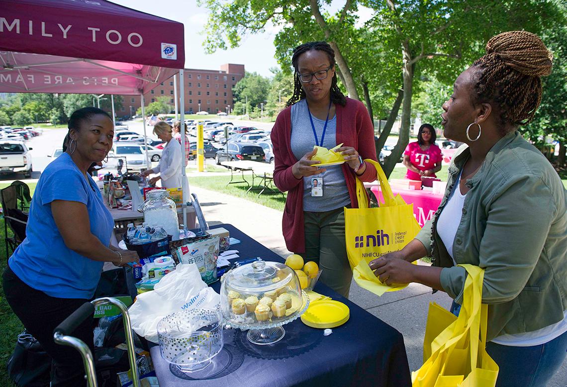 Two women taste cupcakes at the market.
