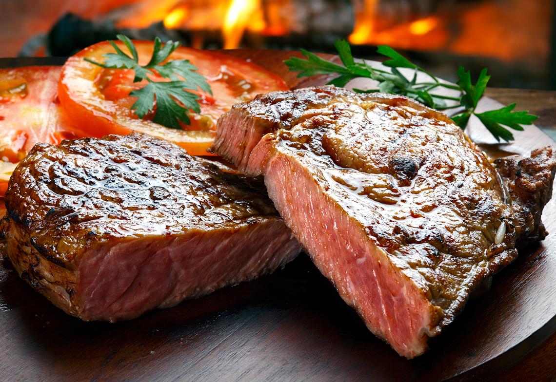 Grilled steak in front of a wood-burning fire.