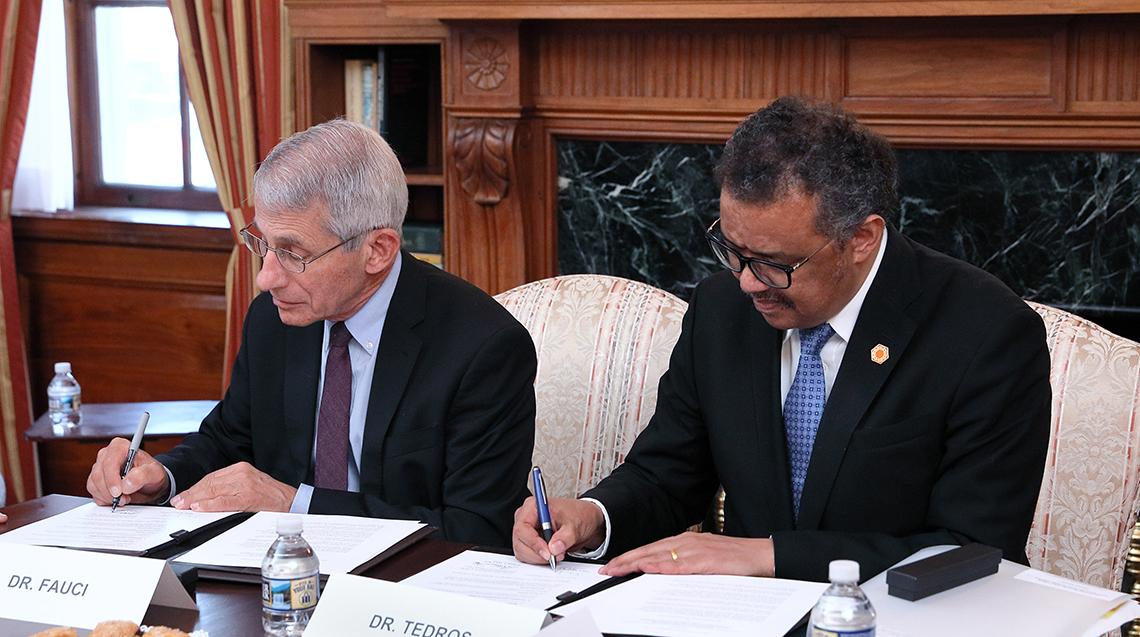 Tedros and NIAID director Dr. Anthony Fauci sign the document.