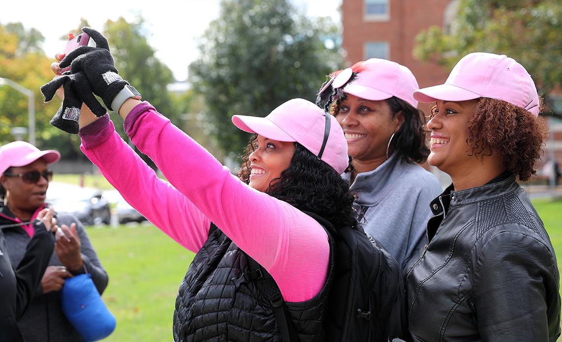 Ladies dressed in pink holding up camera to take a selfie.