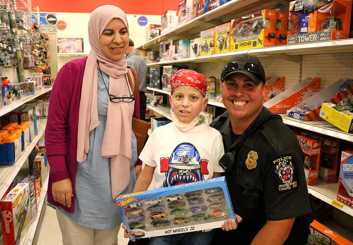 Houssam Merehb and his mom pose with Officer Andrew Martinez while shopping for gifts.