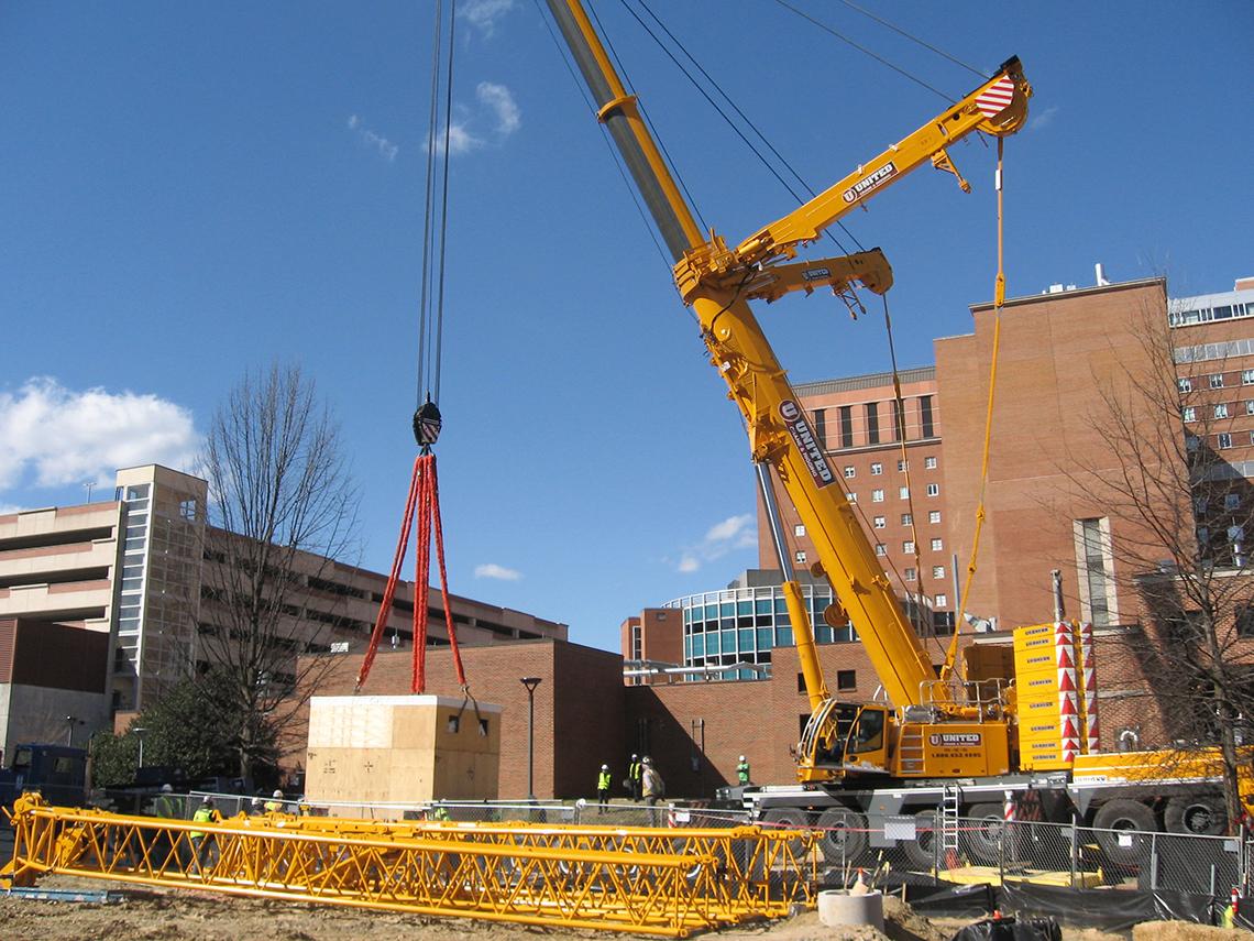 A crane lifts a large box containing a magnet