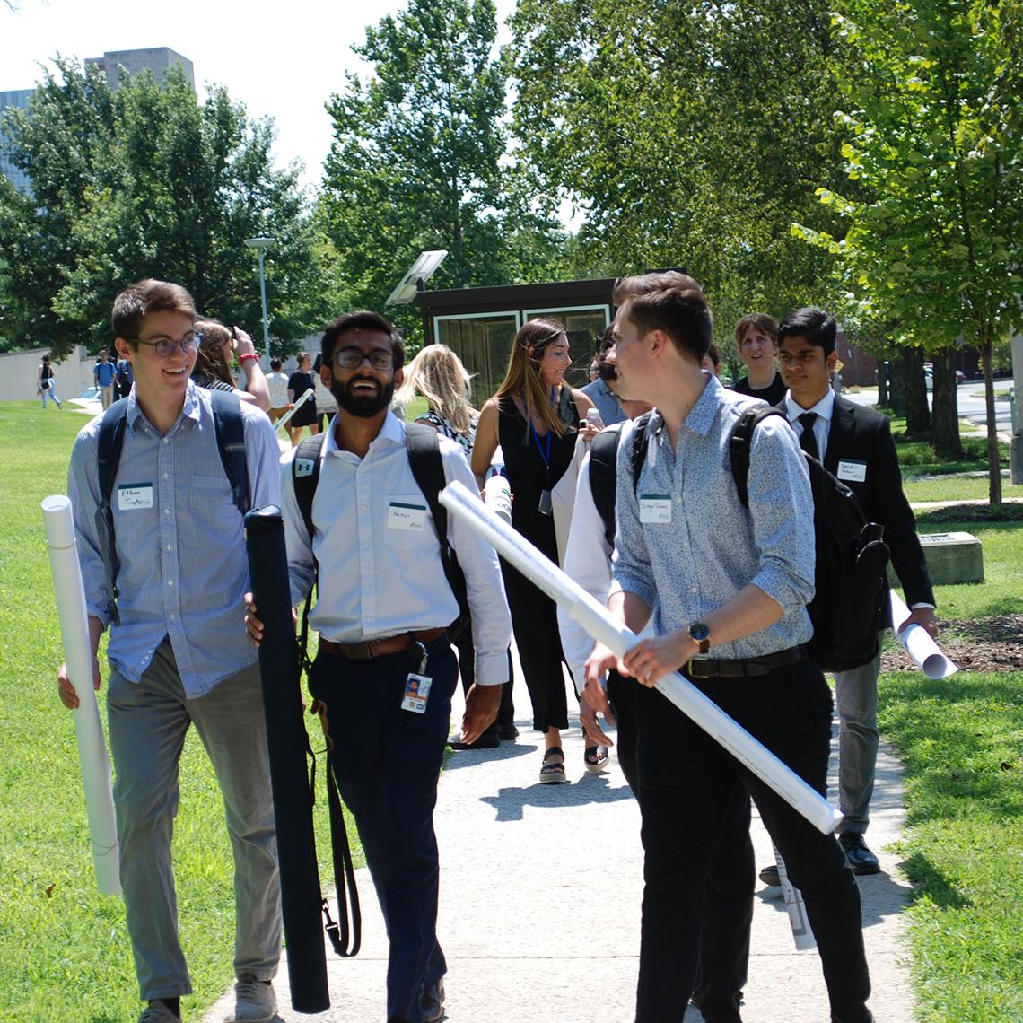 Trainees carry their posters along the sidewalk.