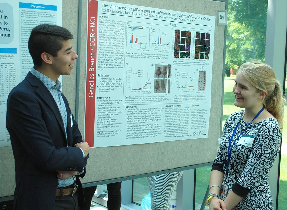 Two trainees talk to each other at a poster exhibit.