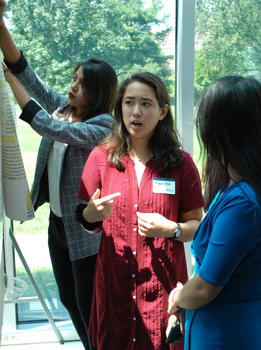 Student discusses her poster with a visitor.