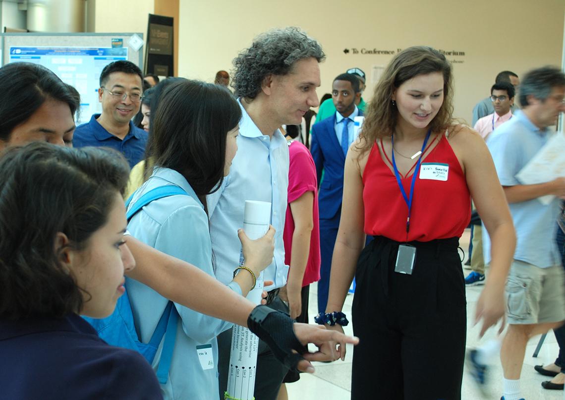 Senior scientist looks at student's work.