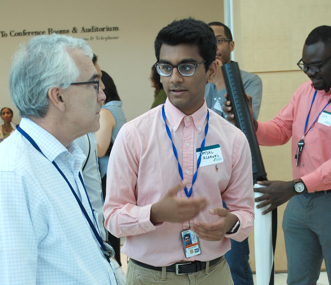 Trainee shows his poster to adult scientist.