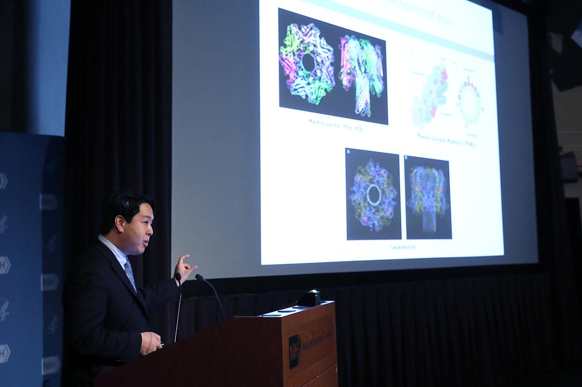 Dr. Chiu stands next to slides