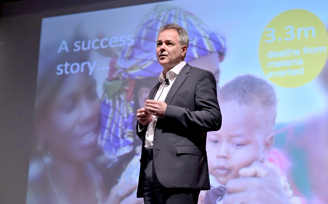 Farrar with slide of women and baby projected behind him.