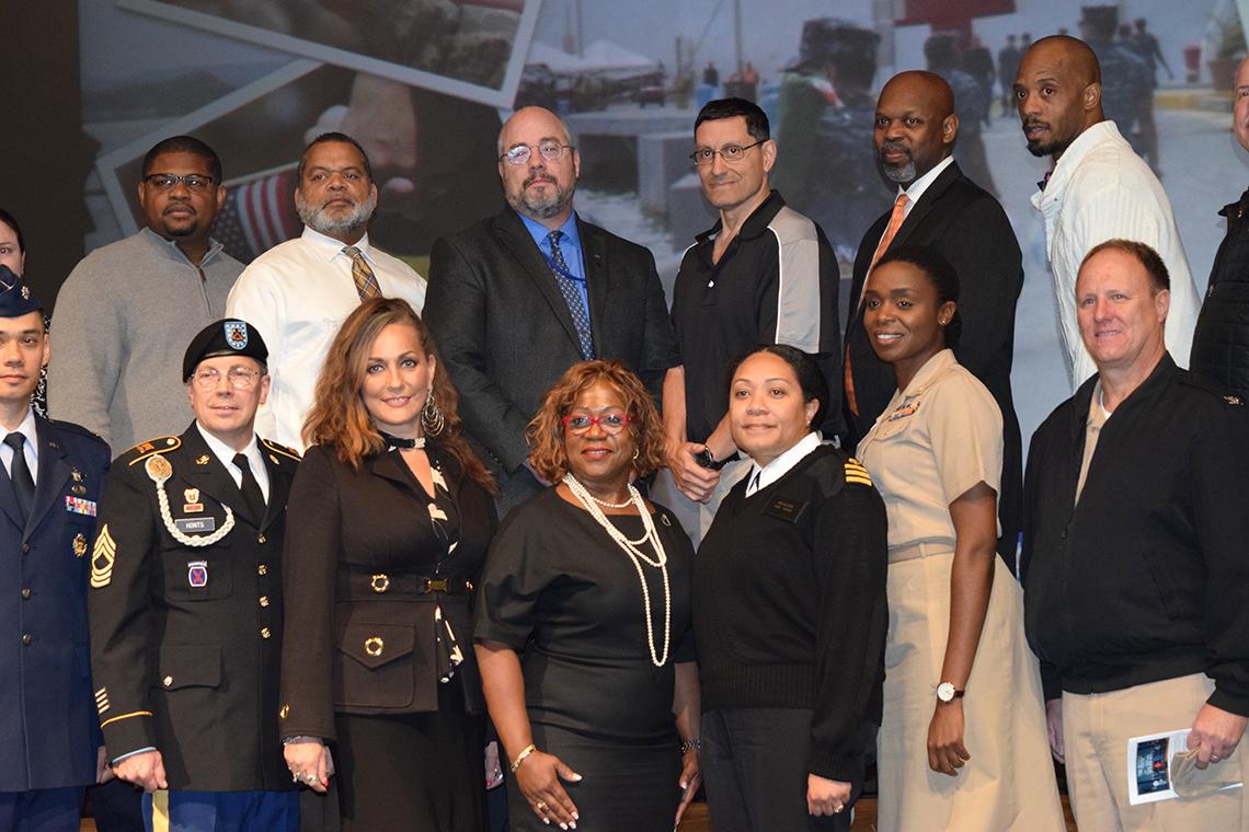 A group of veterans pose for a photo on stage