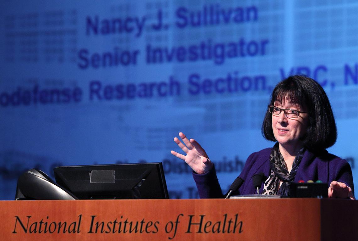 Dr. Sullivan at podium holds out hand to illustrate her research.