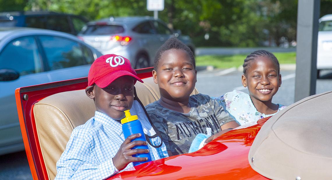 Kids smiling in rumble seat of Cadillac