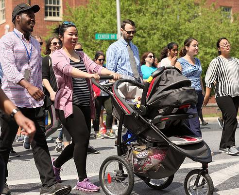Amid other walkers, woman pushes stroller