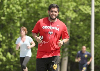 Man runs with earbuds, handheld device